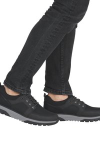 Des baskets de sport noires présentent un dessus en mesh et synthétique, une semelle en caoutchouc grise et des lacets contrastants. Associées à un jean noir slim.