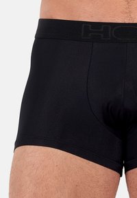 Boxer neri realizzati in tessuto liscio e stretch. Presentano una cintura elastica ampia con logo del marchio e un design a tasca sagomata.