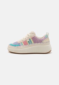 Baskets beiges avec des accents tressés multicolores en rose, vert et bleu. Elles comportent une épaisse semelle blanche striée et des coutures décoratives le long des bords.