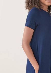 Laivastonsininen lyhythihainen mekko, jossa on rento leikkaus, pehmeä kangas ja sivutaskut. Mekossa on pyöreä pääntie ja sileä pinta.