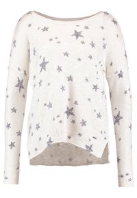 Vit långärmad stickad tröja med spridda grå stjärnmönster och en något längre bakhem.