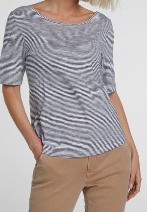 Top a maniche corte a righe in grigio chiaro e blu navy, con scollo ampio e tessuto morbido, abbinato a pantaloni color sabbia per un look casual.