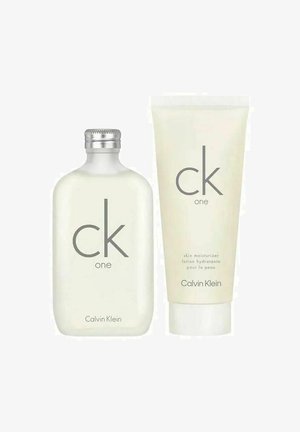 Calvin Kleinin CK One -tuoksupullo, jossa hopeinen korkki, ja sen vieressä CK One -ihon kosteuttajatuubi valkoisella taustalla.
