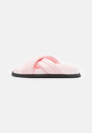 Pink slide sandal med krydsrem, glat materiale og en tekstureret sort gummisål. Flad profil, blød polstring.