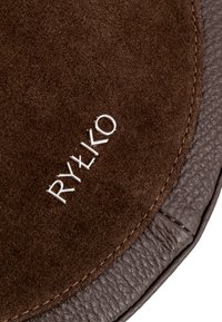 Smeđa kožna torba s mekim suknenim vrhom i teksturiranim tamnosmešim dnom. Ukrašena s "RYŁKO" u sjajnom srebru.