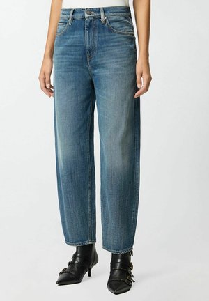 Jeans in denim blu scuro, con vestibilità rilassata, a vita alta, con una texture leggermente sbiadita, cuciture a contrasto e tasche anteriori visibili, abbinati a tacchi neri.