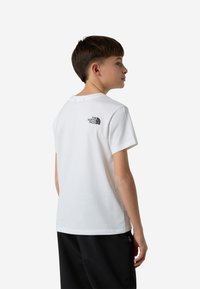 Biały t-shirt z krótkim rękawem wykonany z bawełny, z małym czarnym logo na plecach. Luźny krój z klasycznym okrągłym dekoltem.