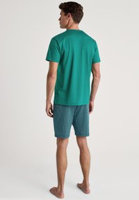 Teal katoenen t-shirt, gecombineerd met gestreepte zwembroek in blauw en witte diamantvormen, ontworpen voor casual gebruik.