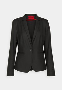 Svart skreddersydd blazer med lange ermer, enkel knappelukking og to frontlommer. Glatt stoff med en subtil glans. Rød innvendig etikett.