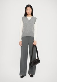 Gray knit vest over a white long-sleeve shirt, paired with gray wide-leg trousers. Accessories include a black shoulder bag and black shoes.