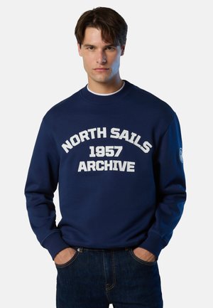 Felpa blu navy con testo bianco "NORTH SAILS 1957 ARCHIVE", collo rotondo, maniche lunghe, polsini a costine e materiale morbido in cotone.