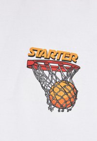 T-shirt blanc avec un graphisme coloré d'un panier de basketball avec un ballon de basketball orange et jaune, et le mot "STARTER" en gras jaune au-dessus.