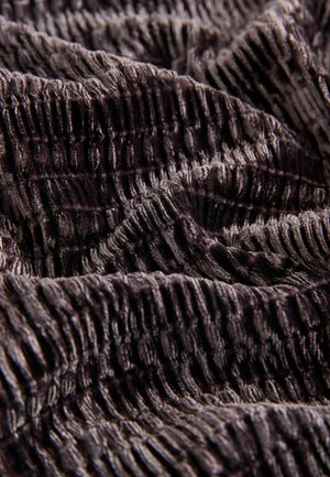 Ciemna, teksturowana tkanina o pomarszczonej powierzchni; charakteryzuje się bogatym, głębokim odcieniem, który podkreśla welurową fakturę i fałdy tkaniny.