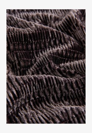 Material texturat închis cu un model de suprafață ridată; prezintă o nuanță bogată, profundă, evidențiind textura catifelată și pliurile materialului.