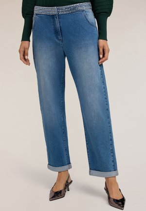 Jeans in denim a gamba larga di blu medio con una vita aderente caratterizzata da borchie argentate. I bordi risvoltati aggiungono un tocco informale.