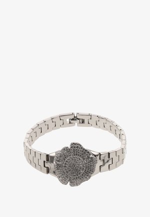 Ezüst fém karkötő virágmintával, texturált részletekkel és középső díszítéssel, dupla záródással rögzítve.