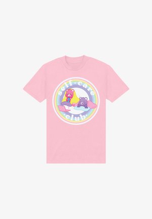 Světle růžové tričko s kulatým potiskem zobrazujícím animované medvědy, dešťovými akcenty a textem "klub péče o sebe" v bílé typografii.