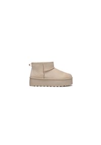 Beige mockask ankle boots med låg profil, vadderad krage, sidostygn och en texturerad plattformssula för grepp och stöd.
