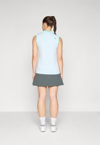 Light blue sleeveless polo shirt with textured fabric and turquoise collar, paired with a dark gray flared skirt, both designed for active wear.