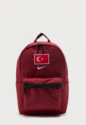 Sac à dos rouge avec poche avant, avec un patch du drapeau turc et un logo Nike swoosh blanc sous le drapeau.