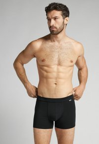 Svarta herrboxershorts i en jämn, elastisk textil, med en bred midjeresår och en figurnära skärning, utformade för komfort och stöd.