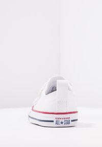 Valged Converse'i spordijalatsid, millel on sile nahk, punased ja sinised aktsendid ning silmapaistev logo kannal. Ümar varba disain.