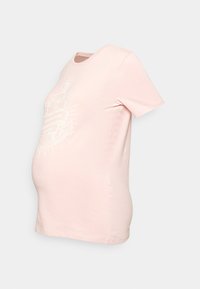 T-shirt de maternidade rosa claro, mangas curtas, gola redonda, com um design gráfico branco estampado com o texto "A AVENTURA COMEÇA." Textura suave.