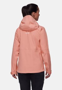 Helle korallenfarbene, wasserdichte Jacke mit Kapuze. Sie hat eine glatte Oberfläche, verstellbare Bündchen und ein Logo auf dem Rücken. Geeignet für den Einsatz im Freien.