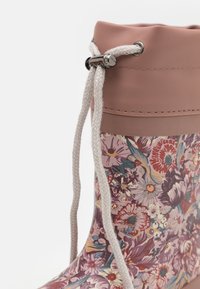 Stivale da pioggia floreale con tomaia in gomma rosa. Presenta un lacci decorativi con hardware metallico e un motivo floreale multicolore testurizzato.