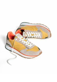 Geel en grijze sneakers met witte veters, oranje accenten en een gestructureerde suède afwerking, met een patroonlogo op de tong.