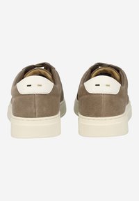 Braune Wildledersneaker mit weißem Fersenstück. Sie verfügen über eine beigen Sohle, ein minimalistisches Design und drei horizontale Streifen in Schwarz, Weiß und Gold.