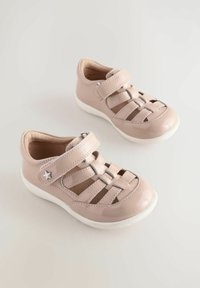 Helles pinke Lackleder-Schuhe mit überkreuzten Riemen, Klettverschluss und weißen Gummisohlen. Mit einem Sternelement an der Seite.