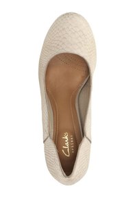 Chaussure beige à enfiler avec un dessus texturé imitant un reptile, doublure intérieure lisse et semelle intérieure rembourrée. Présente le logo "Clarks artisan".