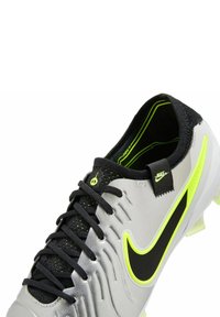 Scarpette da calcio Nike grigie con accenti neri e dettagli giallo brillante. Superficie testurizzata, lacci neri e design affusolato.
