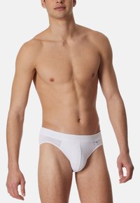 Witte katoenen slip met een zachte elastische tailleband en een naadloos ontwerp. Effen textuur met een klein logo-accent.