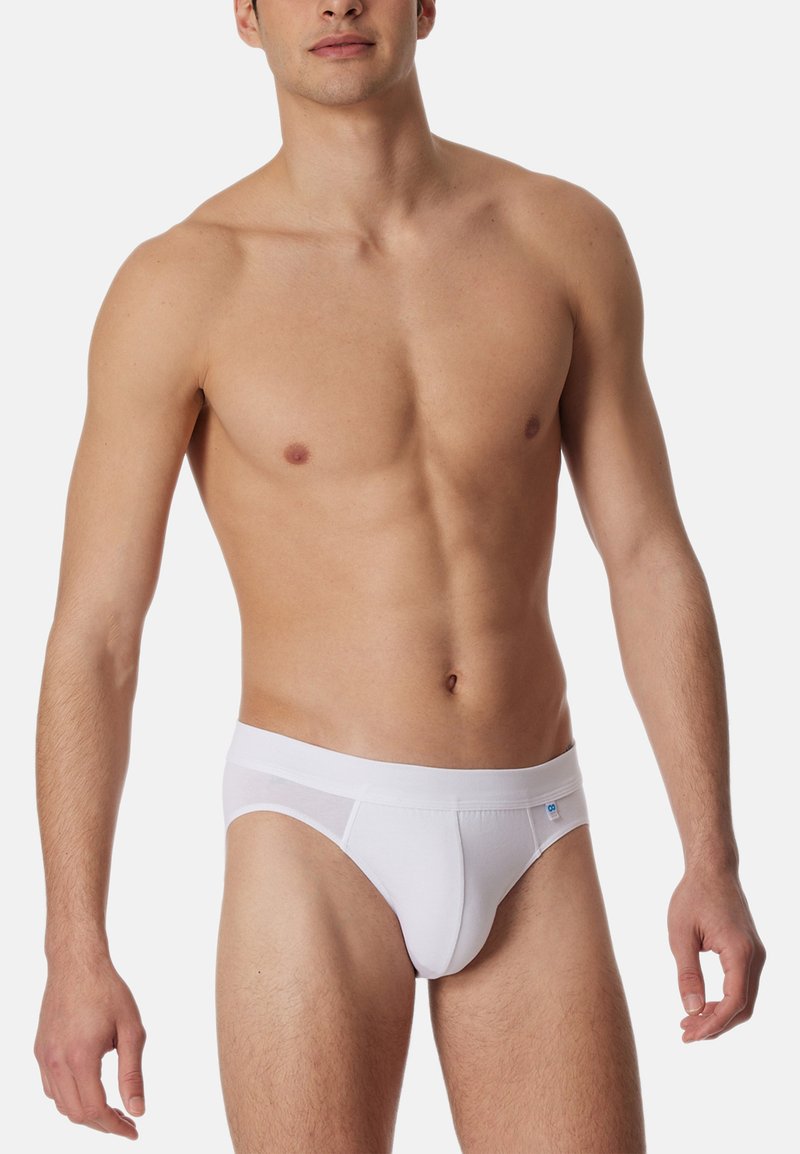 Witte katoenen slip met een zachte elastische tailleband en een naadloos ontwerp. Effen textuur met een klein logo-accent.