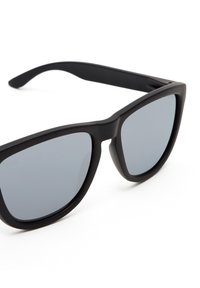 Schwarze Plastiksonnenbrille mit dunkelgrauen Gläsern, rechteckiger Form, glattem mattem Finish und dicken Bügeln. Keine sichtbaren Logos oder Muster.