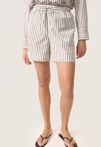 Stribede shorts i hvid og lysebrun, lavet af letvægtsstof. Har en elastisk talje med snøre og opholdte kanter.