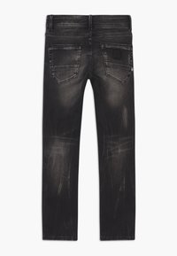 Jeans de mezclilla negra con un acabado desgastado, cinco bolsillos y detalles de costura. Presenta un logo en la etiqueta trasera de la cinturilla.