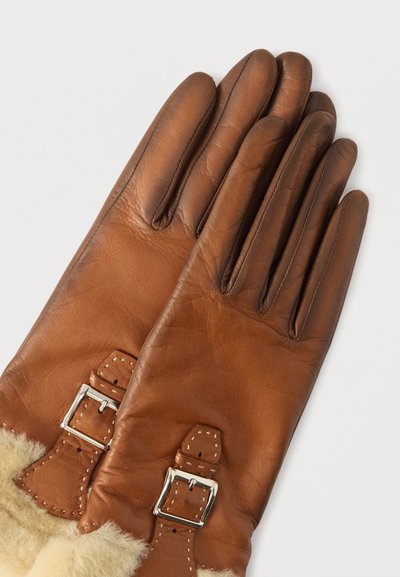Καφέ δερμάτινα γάντια με απαλή επένδυση από shearling, διακοσμημένα με ασημένιες αγκράφες και ραμμένες λεπτομέρειες. Σχεδιασμός με πέντε δάχτυλα και ομαλή υφή.
