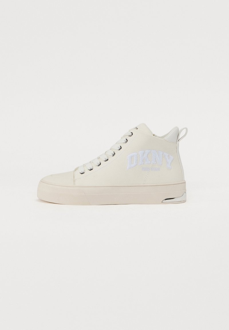 Høy-top sneakers i kremfarget lerret med hvit DKNY-logo på siden, med metallhull, flate lisser og gummisåle.
