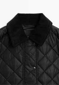 Veste matelassée noire avec grand col en velours côtelé et fermetures à boutons-pression à l'avant.