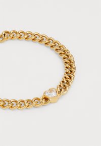 Goldene Kettenarmband mit verflochtenen Gliedern und einem herzförmigen, klaren Edelsteinanhänger.