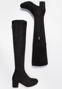 Botas negras de ante por encima de la rodilla, con punta redonda, tacón cuadrado y cremallera lateral para ponérselas fácilmente. Textura suave en todo su diseño.