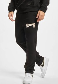 Melni svārki iz kokvilnas ar mīkstu tekstūru, "Rocawear" logo krēmkrāsā un brīvu piegriezumu. Kombinēti ar baltām un melnām kedām.