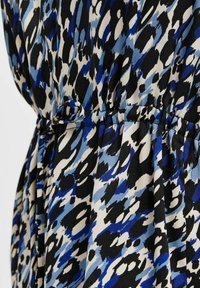 Tkanina drukowana w niebiesko-czarnym kolorze z kremowym abstrakcyjnym wzorem. Elastyczny pasek w talii z detalem w postaci sznurka. Gładka tekstura i zwiewny fason.