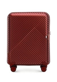 Maleta rígida roja con textura estriada diagonal, cuatro ruedas y cierre lateral con cremallera.