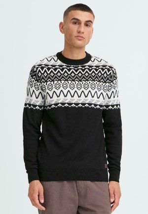 Suéter negro con un yugo blanco decorado con patrones que presentan diseños geométricos, cuello redondo y puños y dobladillo acanalados. Textura suave.