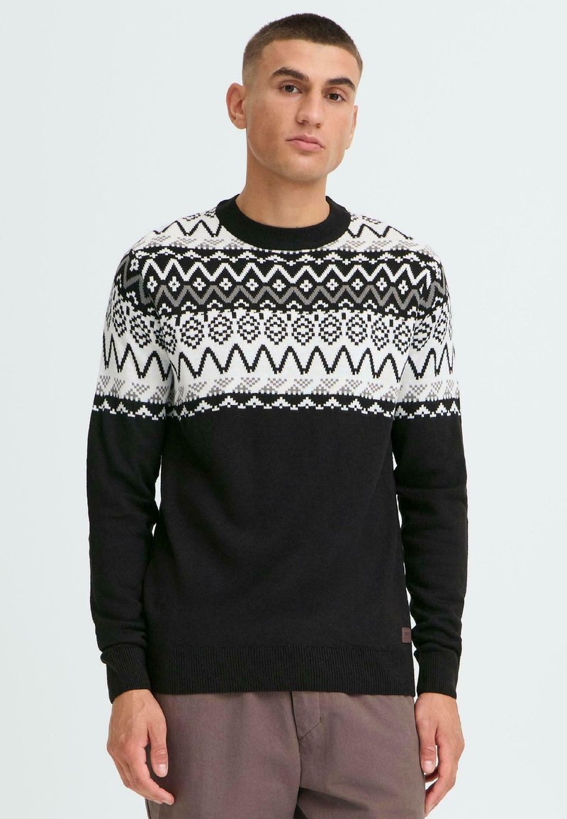 Schwarzer Pullover mit einem weißen gemusterten Einsatz, der geometrische Designs zeigt, runder Ausschnitt sowie gerippte Bündchen und Saum. Glatte Textur.