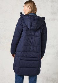 Námořnický puffer kabát s kapucí, se zářezovými prošívanými sekcemi a střední délkou. Materiál se jeví jako hladký a zateplený.